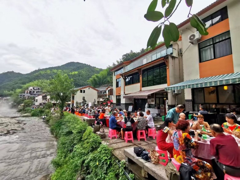 游客和村民在花溪村屋外河边一起吃饭.jpg